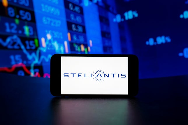 Das Stellantis-Logo wird auf dem Bildschirm eines Mobiltelefons angezeigt, im Hintergrund sind Börsenprozentsätze zu sehen